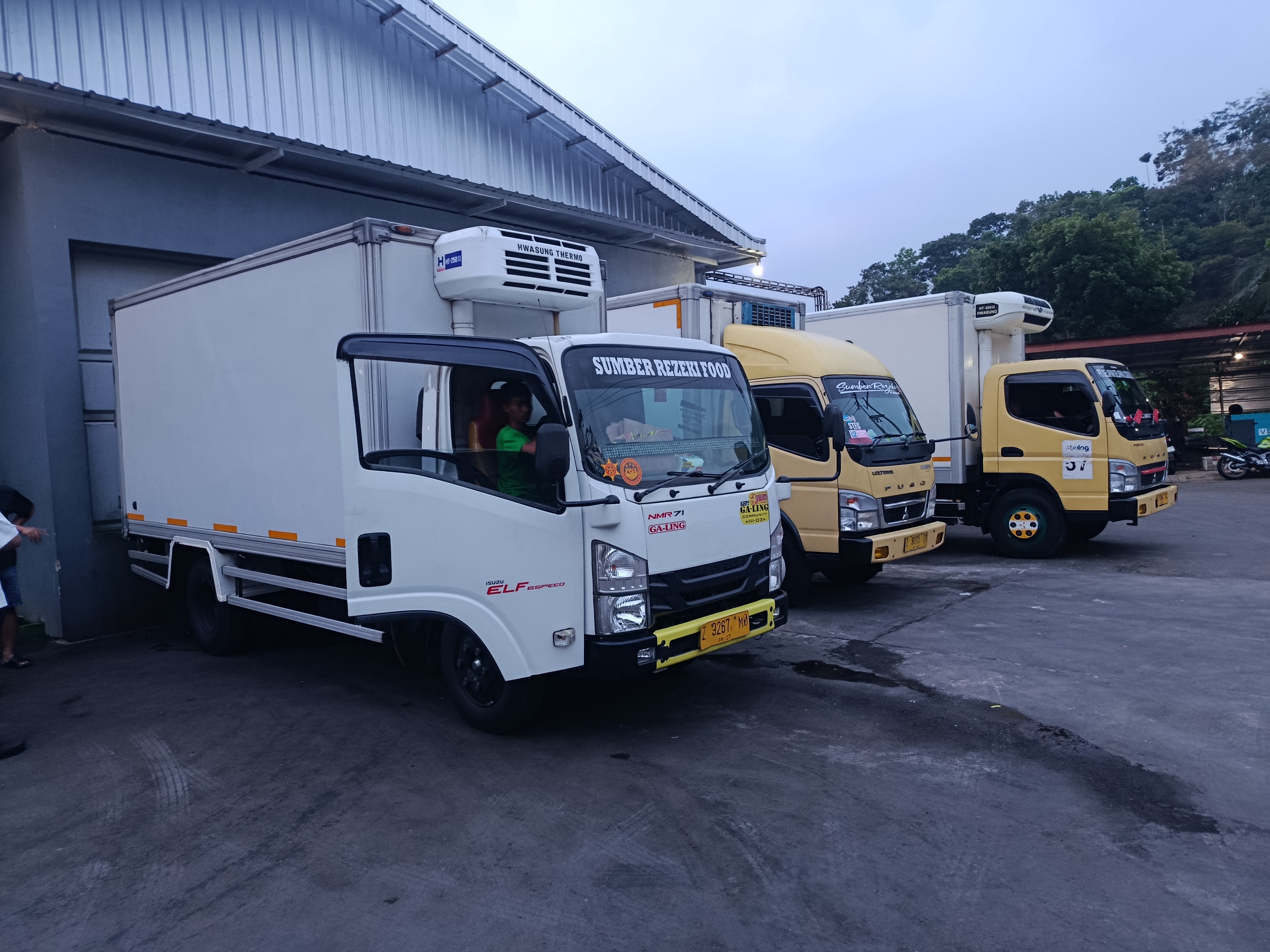 Truk distribusi makanan berwarna putih bersih di lingkungan industri terang siang hari